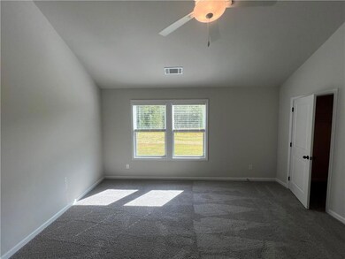 Spare room featuring carpet flooring, baseboards, ceiling fan, and lofted ceiling