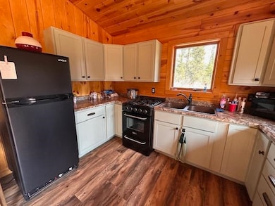 Kitchen featuring black appliances, lofted ceiling