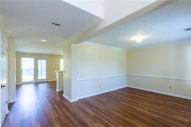 Spare room with a textured ceiling, dark wood-style floors, baseboards, and crown molding