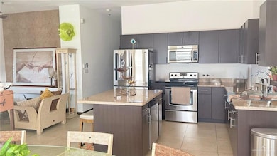 Kitchen with stainless steel appliances, light tile patterned floors, a kitchen bar, and a sink