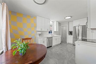 Kitchen with white cabinets, appliances with stainless steel finishes, and wallpapered walls