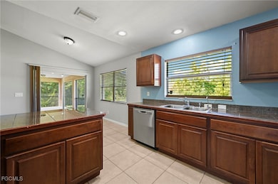 Kitchen featuring tile counters, stainless steel dishwasher, light tile patterned floors, lofted ceiling, and recessed lighting