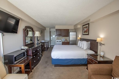 Carpeted bedroom with stainless steel fridge and a
