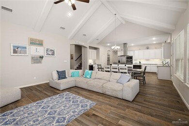 Living room featuring beam ceiling, dark hardwood / wood-style flooring, ceiling fan with notable chandelier, and high vaulted ceiling