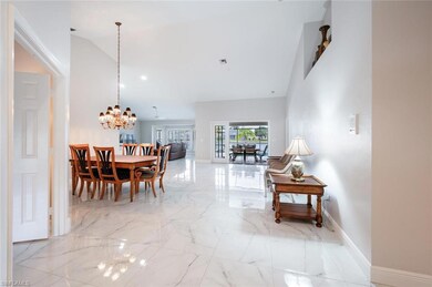 Dining room featuring marble tiled flooring, high vaulted ceiling, a chandelier, and baseboards