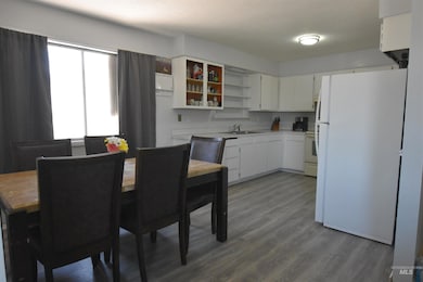 Kitchen featuring white appliances, dark wood finished floors, white cabinets, and light countertops