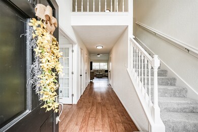 From the covered front porch, a six-panel solid wood front door opens into this light and bright foyer with a soaring two-story ceiling, new texture and fresh neutral paint, and beautiful wood-look laminate flooring.