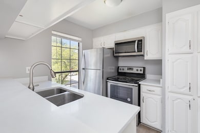 Kitchen featuring white cabinetry, light counterto