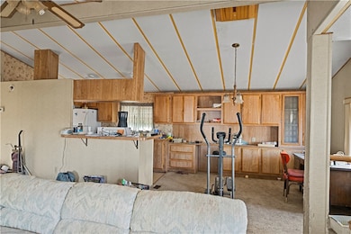 Kitchen with vaulted ceiling, hanging light fixtures, brown cabinetry, open shelves, and white fridge with ice dispenser