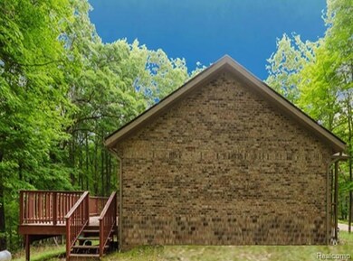 View of side of home featuring brick siding and a wooden deck