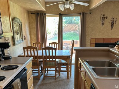 Kitchen featuring a textured wall, range with electric cooktop, black dishwasher, dark tile patterned flooring, and ceiling fan