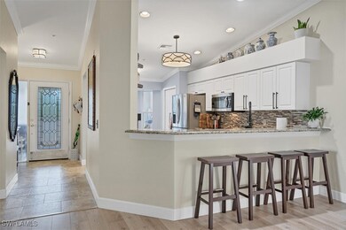 Kitchen featuring stainless steel appliances, baseboards, decorative backsplash, light stone countertops, and a breakfast bar