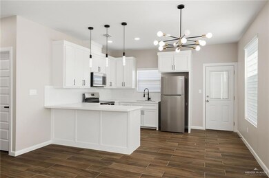 Kitchen with stainless steel appliances, pendant lighting, white cabinets, a peninsula, and recessed lighting