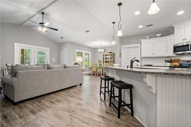 Living room featuring a ceiling fan, dark wood-style flooring, lofted ceiling, recessed lighting, and a chandelier
