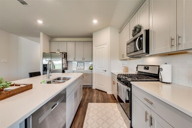 Kitchen featuring stainless steel appliances, dark hardwood / wood-style floors, tasteful backsplash, white cabinets, and sink