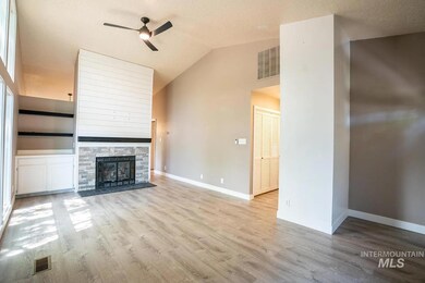 Unfurnished living room with ceiling fan, wood finished floors, vaulted ceiling, a fireplace, and a textured ceiling