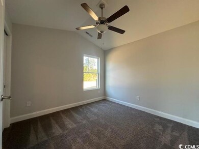 Spare room featuring a ceiling fan, lofted ceiling, baseboards, and dark colored carpet
