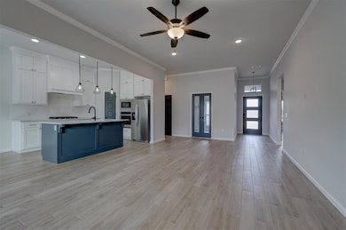 Kitchen with a kitchen island with sink, hanging light fixtures, white cabinetry, and appliances with stainless steel finishes