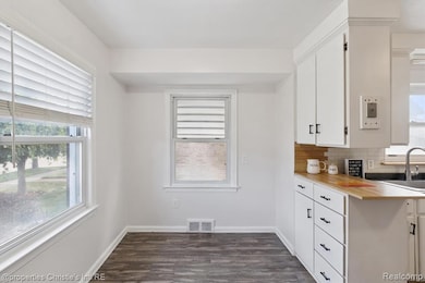 Kitchen with light countertops, white cabinets, dark wood-style flooring, and decorative backsplash