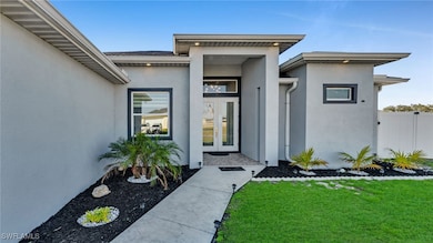 View of exterior entry with french doors and a law
