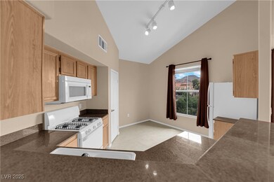 Kitchen with white appliances, dark stone counters
