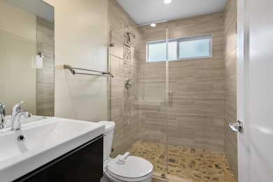 Bathroom with toilet, vanity, and a stall shower