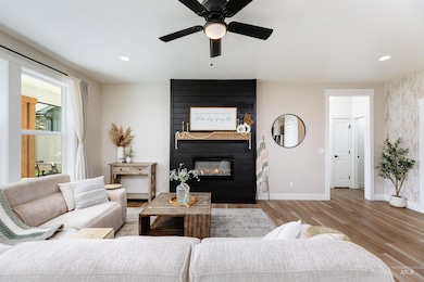 Living room with a large fireplace, wood finished floors, ceiling fan, and recessed lighting