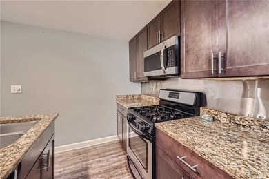 Kitchen featuring dark brown cabinetry, light ston