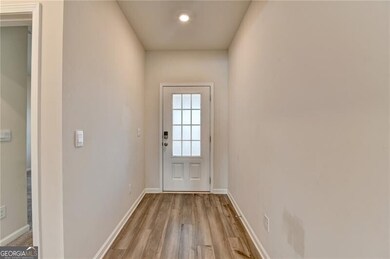 Doorway to outside featuring baseboards and light 