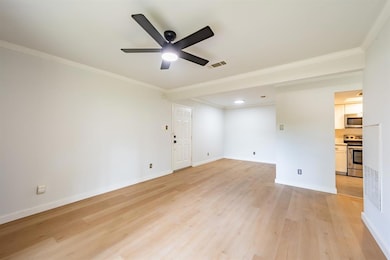 Unfurnished room featuring ornamental molding, light wood-style flooring, and a ceiling fan
