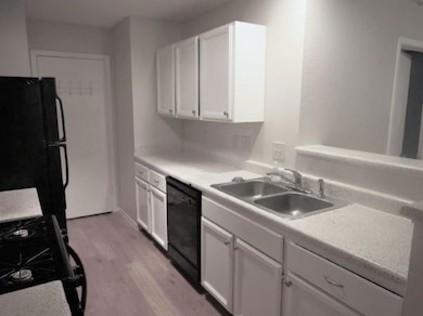 Kitchen with a sink, white cabinets, black applia