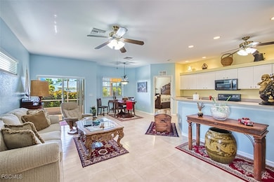 Living area with a ceiling fan, light tile patterned floors, and recessed lighting