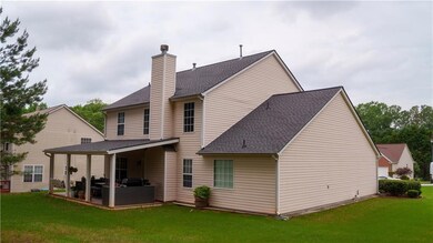 Back of house with a patio, a yard, a chimney, and roof with shingles