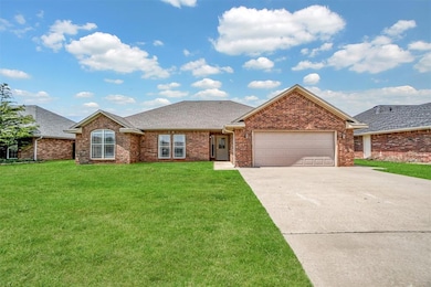 Single story home featuring a garage, concrete driveway, a front yard, and brick siding