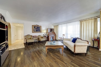 This spacious living area features crown molding, wood tile flooring, and access to a private balcony. This unit is designed for entertaining.