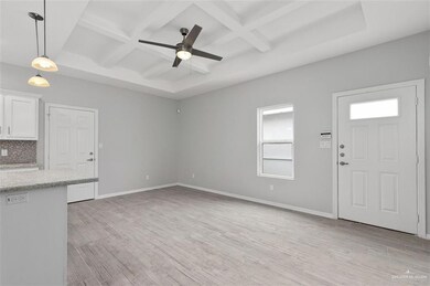 Unfurnished living room with coffered ceiling, plenty of natural light, beam ceiling, a ceiling fan, and light wood-style floors