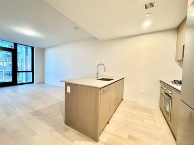 Kitchen with a peninsula, modern cabinets, a wall of windows, light wood-style flooring, and light stone countertops