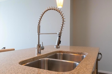 Kitchen view of a sink and light stone counters