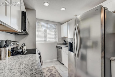 Kitchen featuring appliances with stainless steel finishes, white cabinets, baseboards, and recessed lighting