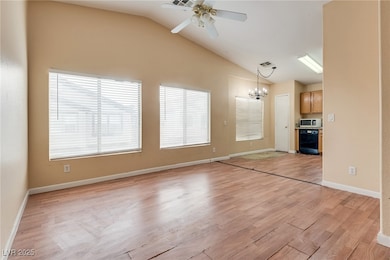 Unfurnished living room with light wood-style floors, a chandelier, lofted ceiling, and ceiling fan