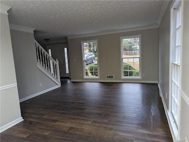 Spare room featuring ornamental molding, a healthy amount of sunlight, and dark wood-type flooring