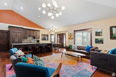 Living room featuring dark wood-type flooring, a chandelier, and high vaulted ceiling
