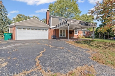 View of front of property with a patio area, brick siding, driveway, a chimney, and french doors