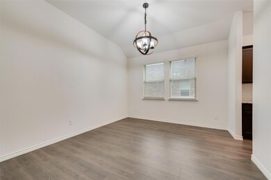 Empty room featuring lofted ceiling, wood-type flooring, and a chandelier