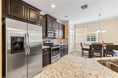 Kitchen with pendant lighting, dark brown cabinetry, an inviting chandelier, backsplash, and appliances with stainless steel finishes