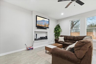 Living room featuring ceiling fan and light wood-t