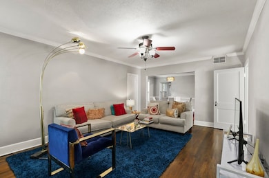 Living area with ornamental molding, dark wood finished floors, a textured ceiling, and a ceiling fan