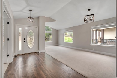 Entryway featuring healthy amount of natural light, vaulted ceiling, and wood finished floors