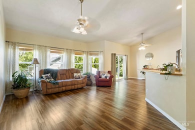 Living area with a ceiling fan, plenty of natural light, dark wood-type flooring, and lofted ceiling