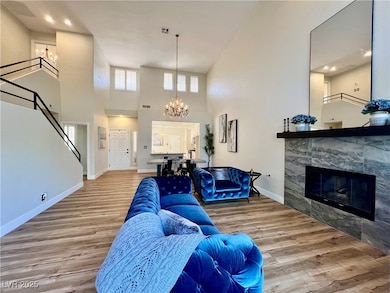 Living room featuring a chandelier, wood finished floors, a towering ceiling, stairway, and a fireplace